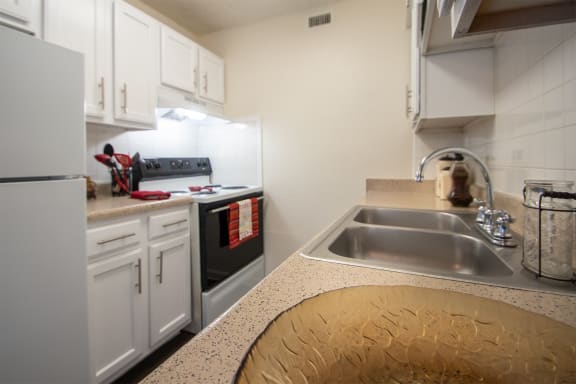 a kitchen with a sink and a stove and white cabinets