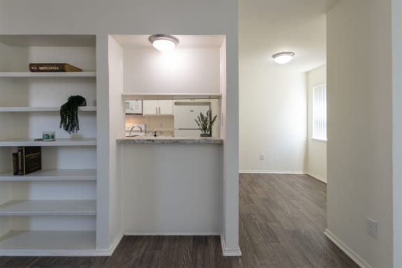 This is a photo of the kitchen breakfast bar and living room built-in shelving in the 970 square foot 2 bedroom, 2 bath apartment at Preston Park Apartments in Dallas, TX