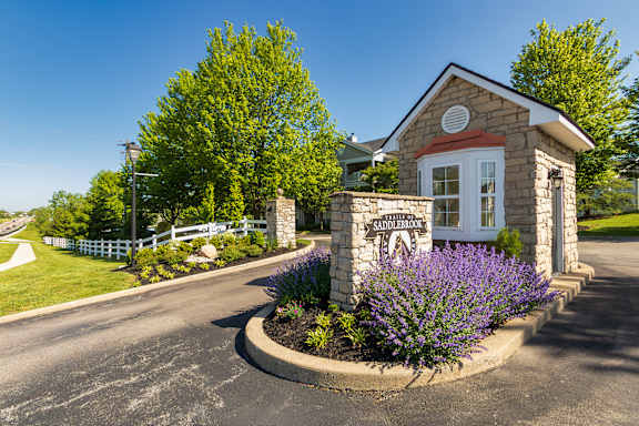 A small stone building with a sign that reads "SANDERSON" sits in front of a well-manicured lawn and a tree.