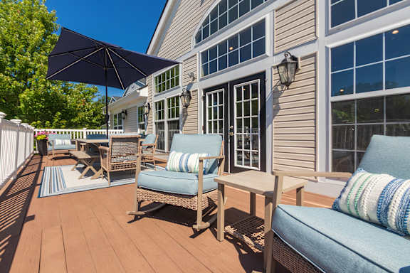 A patio with a blue couch and a black umbrella.