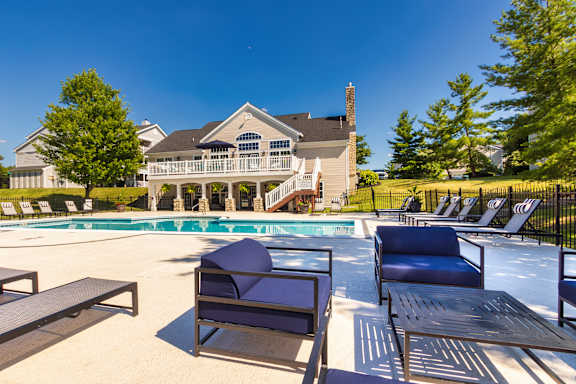 A large house with a pool and lounge chairs.