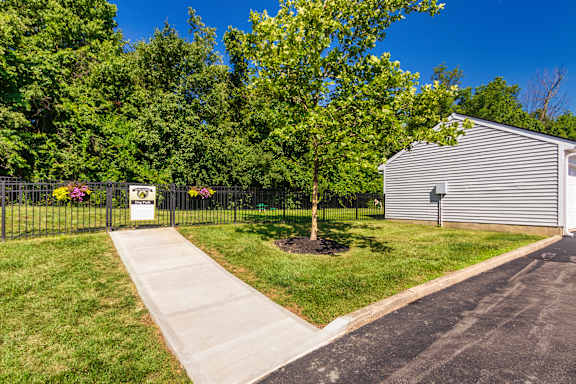 A sign is on a fence in front of a green tree.