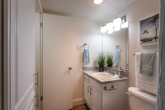 A bathroom with a white vanity in the 558 square foot 1 bedroom, 1 bath model apartment at The Summit at Midtown Apartments in the Dallas Midtown neighborhood of Dallas, TX.