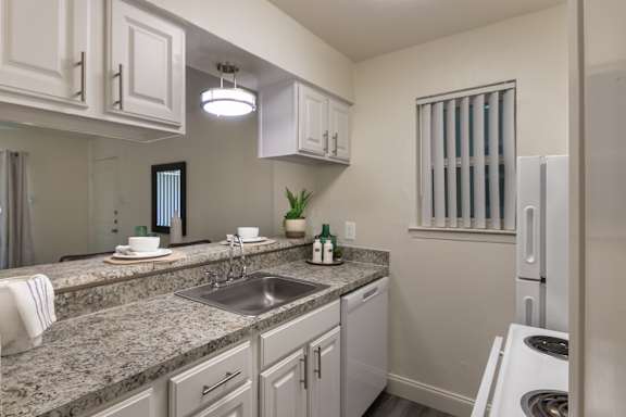 Kitchen with white cabinetry, granite-style countertops, double sink, and breakfast bar in the 558-square-foot 1 Bedroom, 1 Bath A at The Summit at Midtown