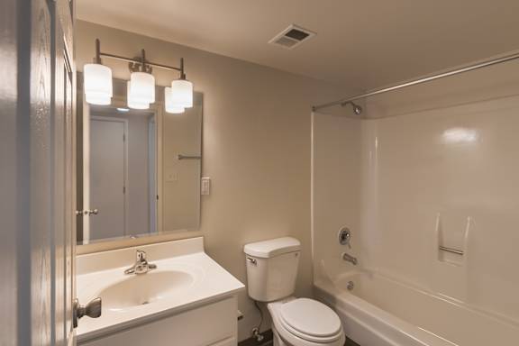 Bathroom in the Village East 684 sq. ft. apartment, with a vanity, mirror, toilet, and tub/shower combination.