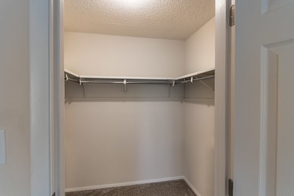 Walk-in closet in the 684 sq. ft. 1-bedroom apartment at Village East Apartments, with carpeted flooring, hanging rods, and shelf storage.