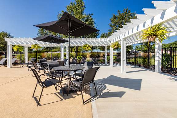 A patio with a table and chairs under a black umbrella.