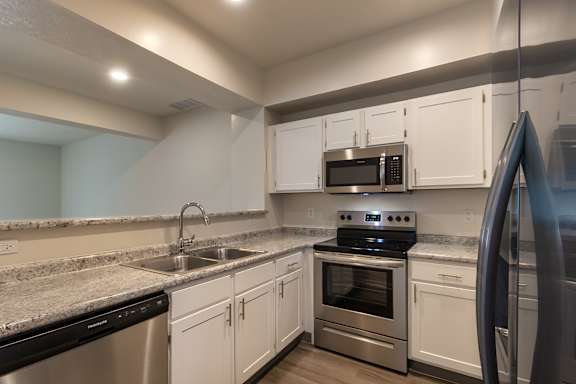 A kitchen with white cabinets and stainless steel appliances in the 1280 square foot, 2 bedroom, 2 and a half bath Oakwood floor plan  at Washington Park Apartments, in Centerville, OH.