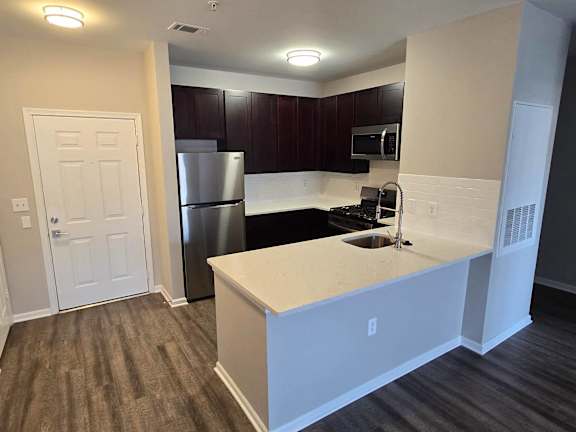 A kitchen with a white counter top and dark brown cabinets.at Riverview Landing @ Valley Forge, Pennsylvania