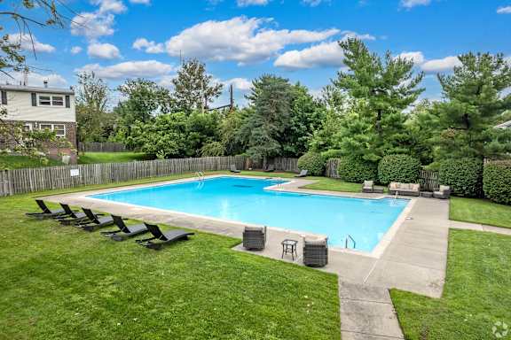 A swimming pool surrounded by a grassy area and trees at Brookshire Trace Townhomes Apartments, Philadelphia, 19116