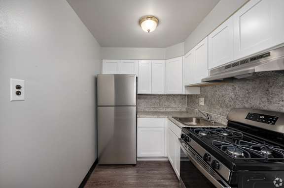 A kitchen with a stainless steel refrigerator and a black stove top oven.