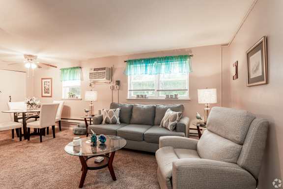A living room with a grey couch, a glass coffee table, and a grey armchair.