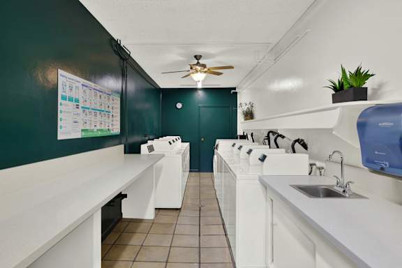a laundry room with a row of sinks and a ceiling fan