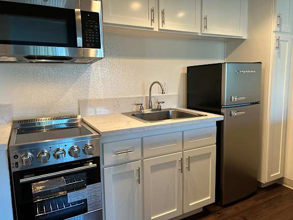 A modern kitchen with a stainless steel refrigerator, oven, and microwave.