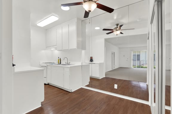 an open kitchen with white cabinets and a ceiling fan at Olive Tree Apartments, Torrance California