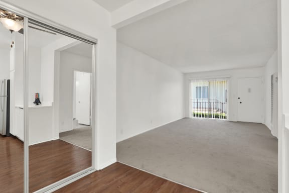 a living room with white walls and a mirrored door at Olive Tree Apartments, Torrance, CA