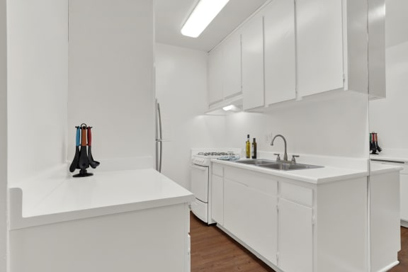 a kitchen with white cabinets and a sink and a refrigerator at Olive Tree Apartments, California, 90503