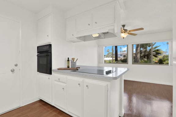 a kitchen with white cabinets and a counter top and a black refrigerator  at Royal Towers Apartments, Redondo Beach, 90277