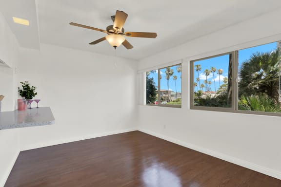 an empty living room with a ceiling fan and windows at Royal Towers Apartments, Redondo Beach, CA