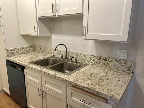 A kitchen with a marble countertop and white cabinets.