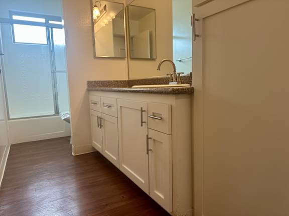 A bathroom with a sink, mirror, and cabinets at Royal Towers Apartments, Redondo Beach, CA, 90277