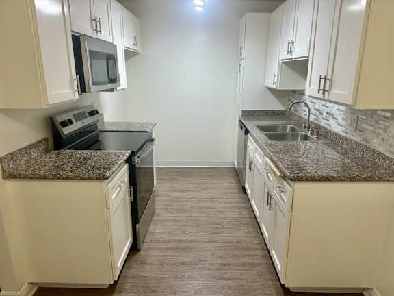 A kitchen with granite countertops and white cabinets.