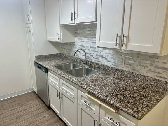 A kitchen with granite countertops and white cabinets.