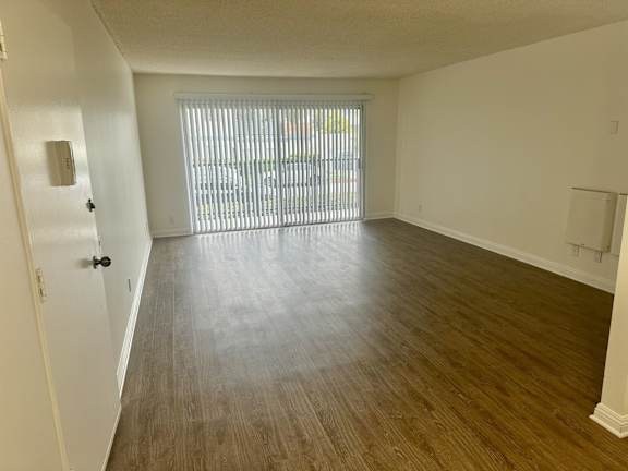 A room with wooden flooring and a sliding glass door.