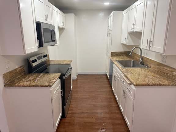 A kitchen with white cabinets and brown countertops.