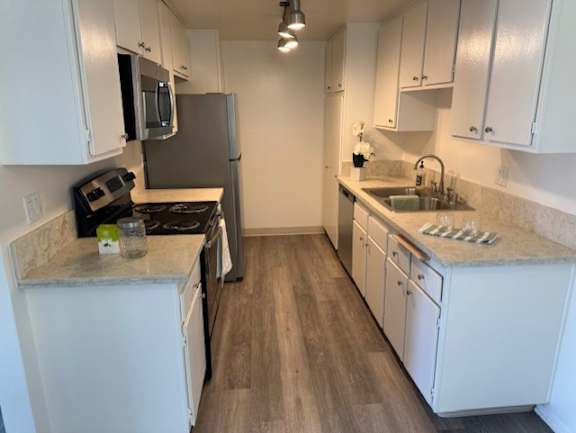 A kitchen with white cabinets and a wooden floor.