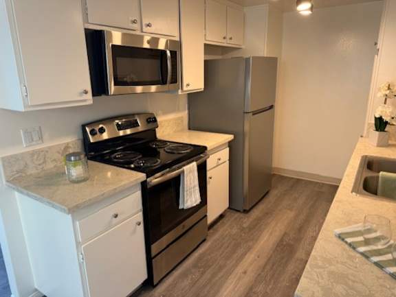 A kitchen with a stove, refrigerator, and microwave.