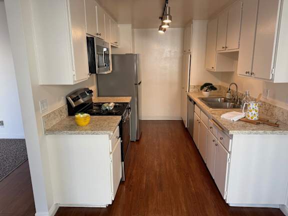 A kitchen with white cabinets and a wooden floor.