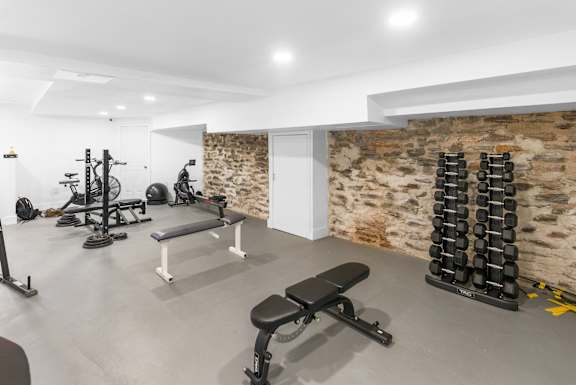 A gym with a variety of equipment including weights and a bench.