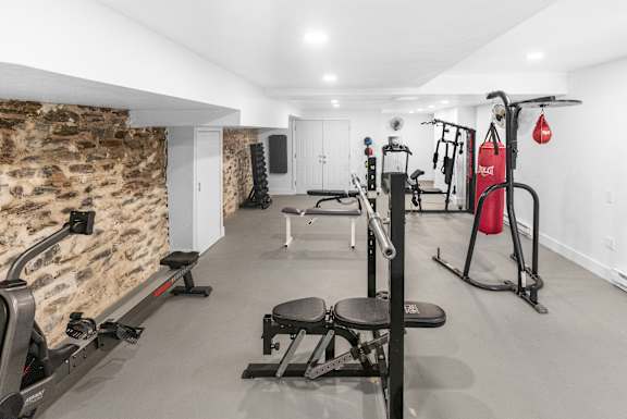 A gym with a variety of equipment including a squat rack, bench, and weights.