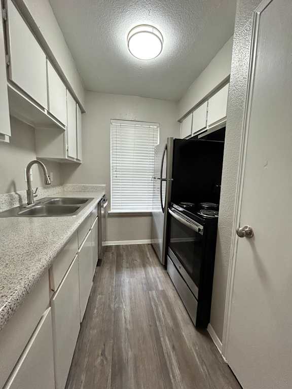A kitchen with a stainless steel refrigerator and white cabinets.