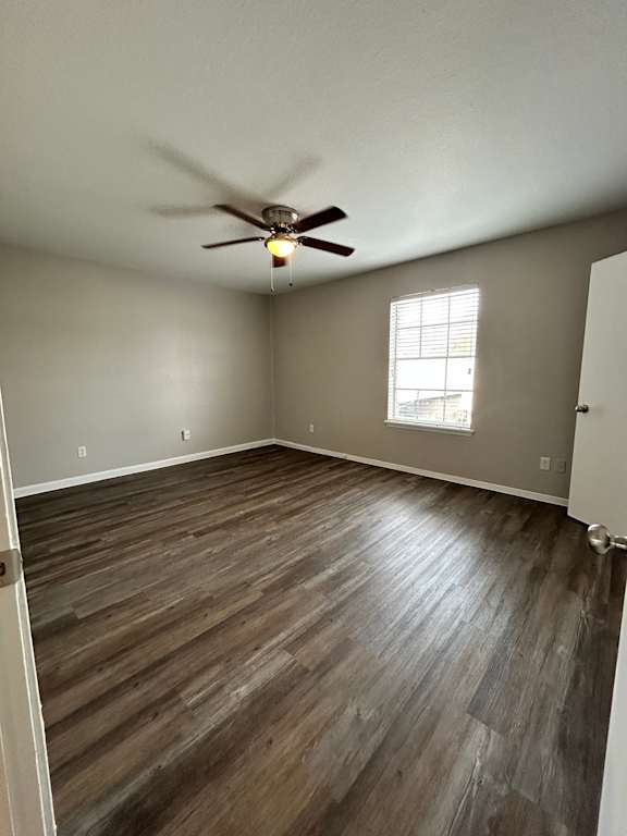 A ceiling fan hangs over a wooden floor in a room.