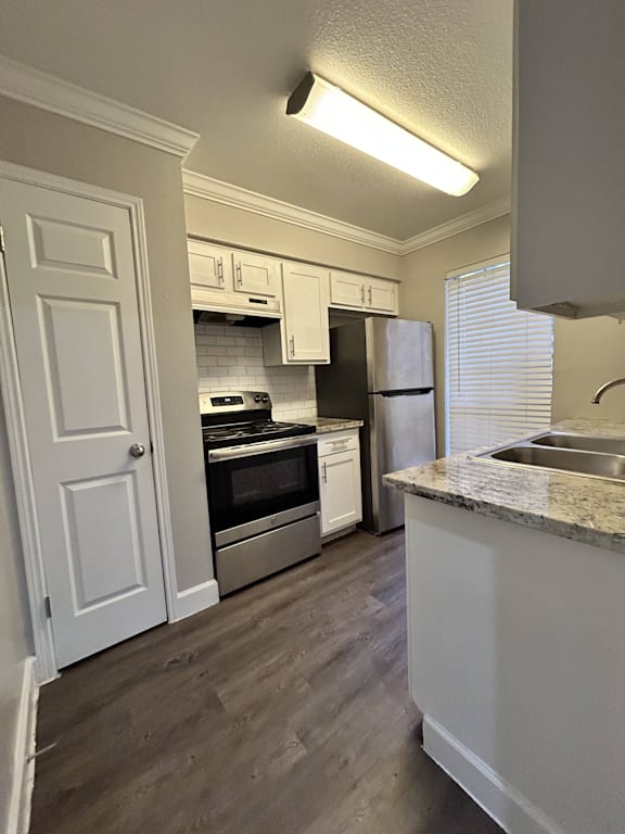 A kitchen with white cabinets and a granite counter.