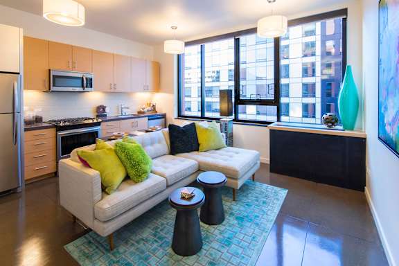 A modern kitchen with a white couch and a blue rug.