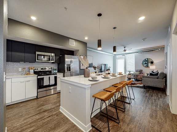 A modern kitchen with a bar area and a living room area.at Linc, Des Moines, 50309