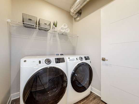 Two white front load washing machines in a laundry room.at Linc, Des Moines