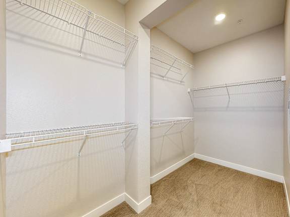 A walk-in closet with white shelving and a tan carpet.at Linc, Des Moines, 50309