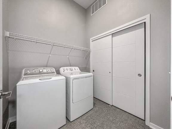 A laundry room with a washer and dryer and a white closet.at Level, Iowa