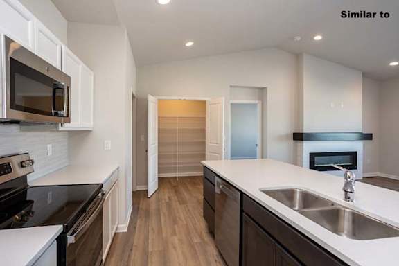 a kitchen with a sink and a stove and a microwave at Two Rivers Home Rentals, West Des Moines, IA 50266