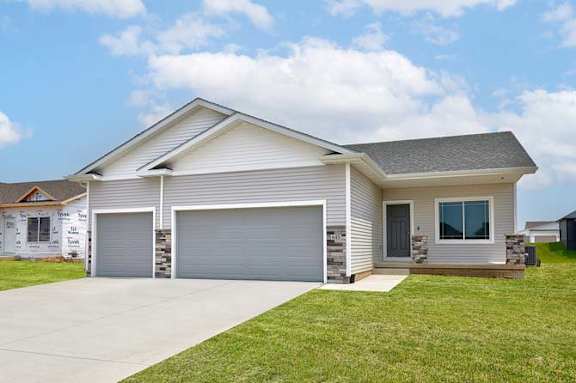 a white house with a driveway and a garage door at Two Rivers Home Rentals, West Des Moines, IA