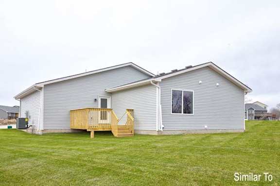 a blue house with a deck in the grass at Two Rivers Home Rentals, West Des Moines, IA 50266