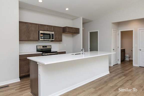 A kitchen with a white countertop and brown cabinets. at Two Rivers Home Rentals, West Des Moines, 50266