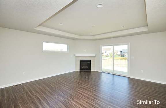 an empty living room with a fireplace and wooden floors at Two Rivers Home Rentals, Iowa