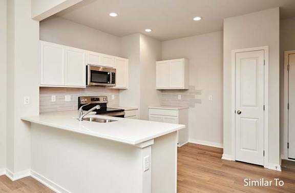 a white kitchen with a sink and a microwave at Two Rivers Home Rentals, Iowa 50266
