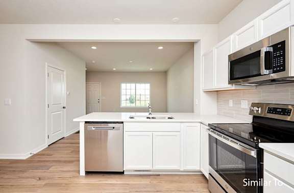 a white kitchen with a microwave and a sink at Two Rivers Home Rentals, West Des Moines, IA 50266