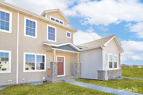 a tan house with a red door and a green yard at Two Rivers Home Rentals, West Des Moines, IA